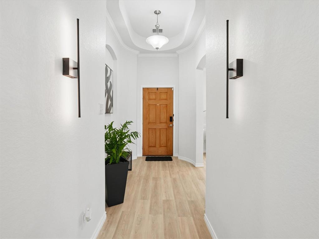 6527 Portside Ridge Lane Dallas, TX 75249 - Photo 7 of 30 a view of a hallway with wooden floor and a potted plant