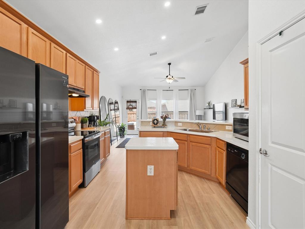 6527 Portside Ridge Lane Dallas, TX 75249 - Photo 10 of 30 a kitchen with stainless steel appliances granite countertop a refrigerator a sink dishwasher a stove and white cabinets with wooden floor