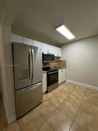 a kitchen with granite countertop a refrigerator and a stove top oven