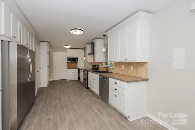 a kitchen with granite countertop a refrigerator stove top oven and sink
