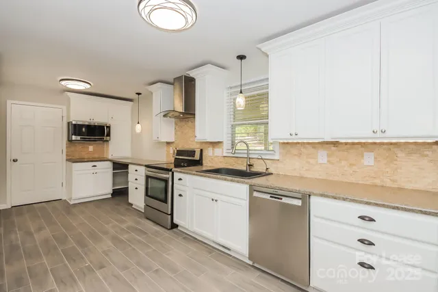 a kitchen with stainless steel appliances granite countertop a sink cabinets and wooden floor