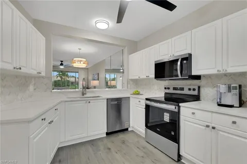 a kitchen with sink a microwave and cabinets
