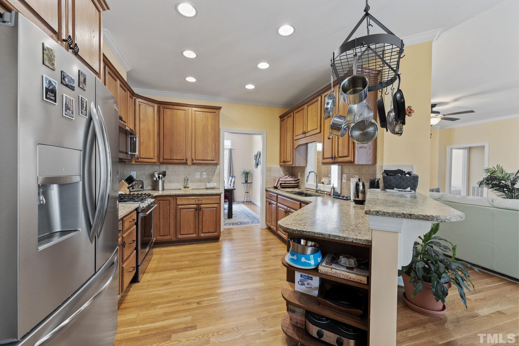 25 Eaglefeather Path Youngsville, NC 27596 - Photo 11 of 36 a kitchen with stainless steel appliances granite countertop a refrigerator a sink dishwasher a stove and a dining table with wooden floor