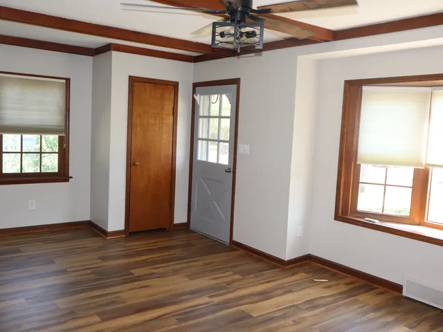 a view of an empty room with wooden floor and a window
