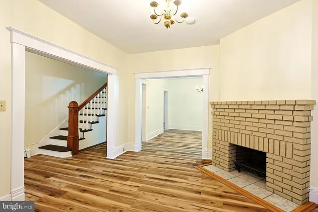 a view of an empty room with wooden floor and a fireplace