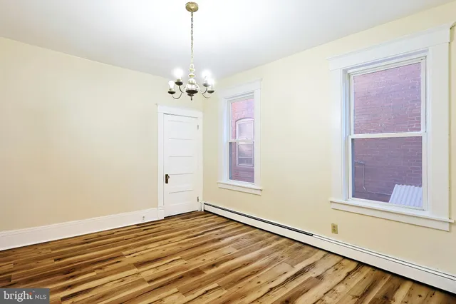 a view of an empty room with window and wooden floor