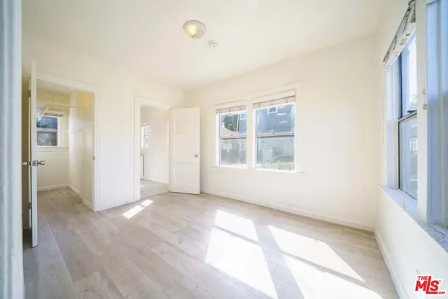 a view of an empty room with window and wooden floor