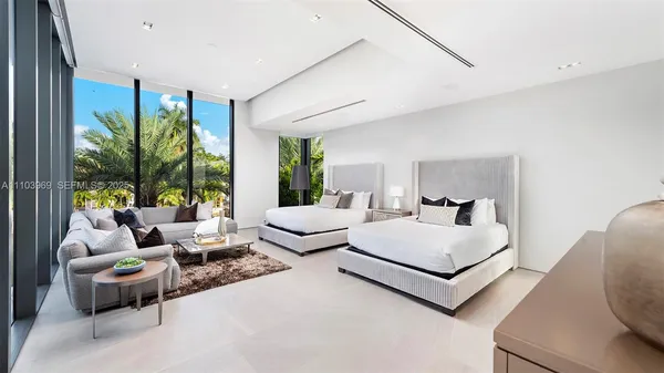 a bedroom with a bed couch painting on wall and a flat screen tv