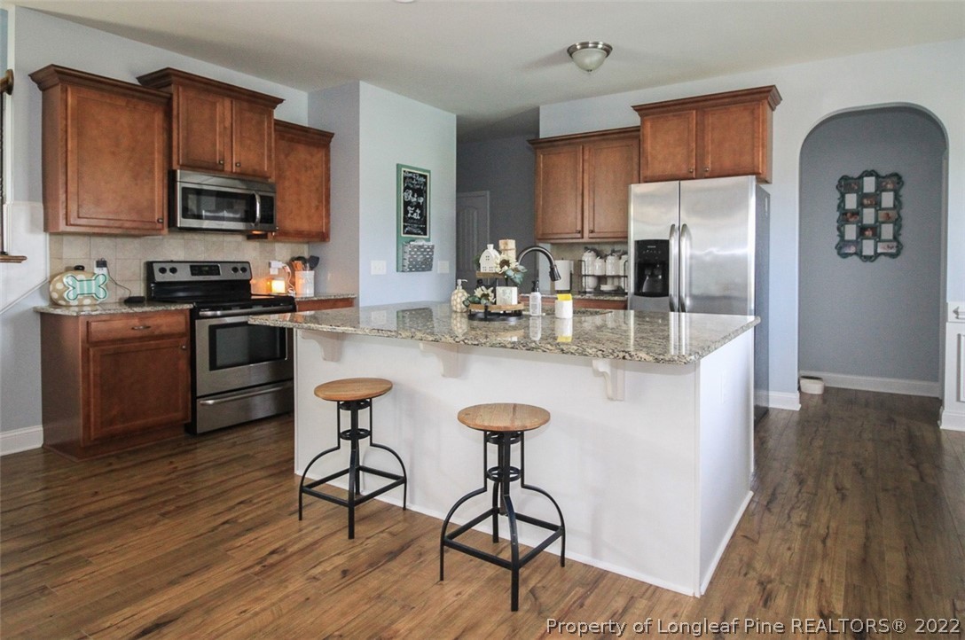 3549 Thrower Road Hope Mills, NC 28348 - Photo 8 of 38 a kitchen with stainless steel appliances granite countertop a refrigerator a stove top oven a sink dishwasher and wooden cabinets with wooden floor