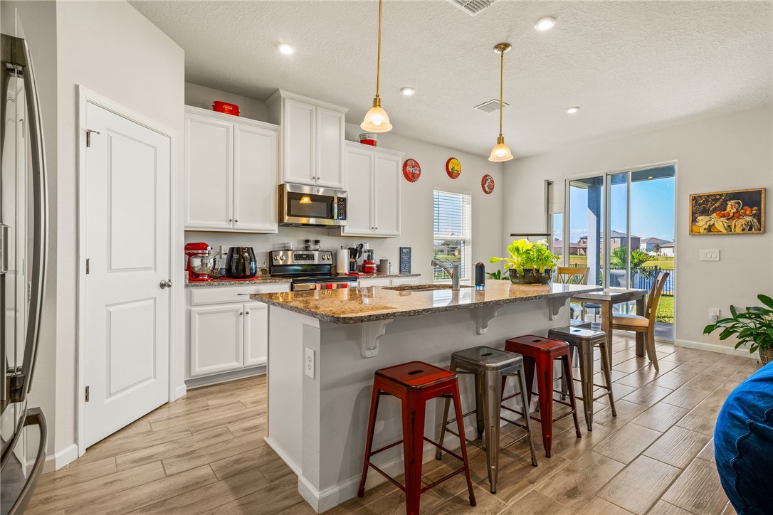 4202 Keeson Circle Vero Beach, FL 32967 - Photo 4 of 36 a kitchen with stainless steel appliances granite countertop a table chairs refrigerator and microwave