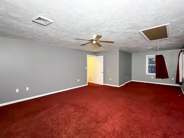 an empty room with windows and ceiling fan