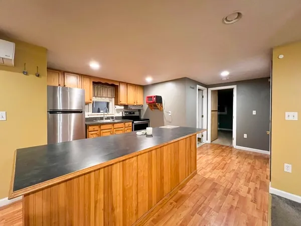 a view of a kitchen with kitchen island a large counter top space stainless steel appliances and cabinets