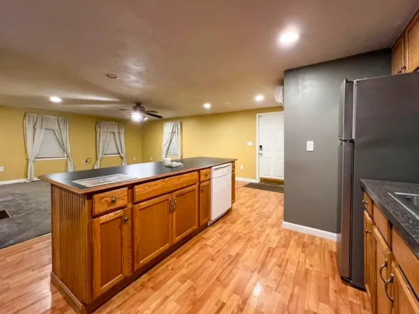 a large kitchen with stainless steel appliances granite countertop a large counter top a sink a refrigerator and a counter top space