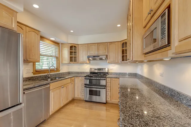 a kitchen with stainless steel appliances granite countertop a stove a sink and a microwave