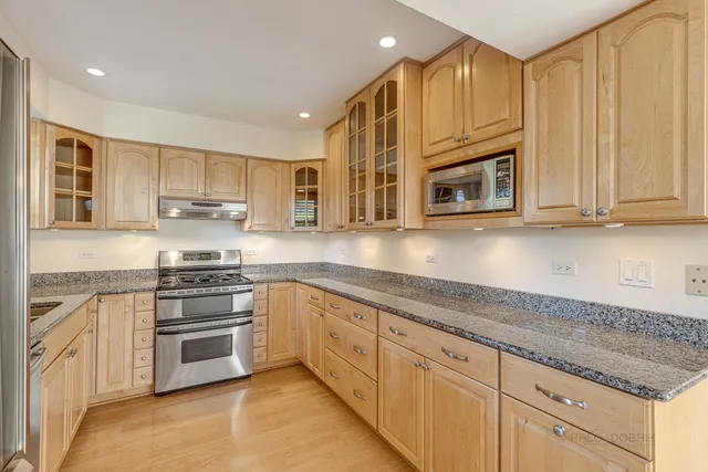 a kitchen with stainless steel appliances granite countertop a stove microwave and cabinets