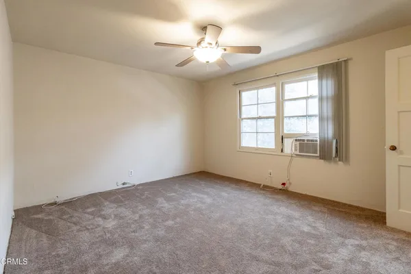 an empty room with chandelier fan and windows