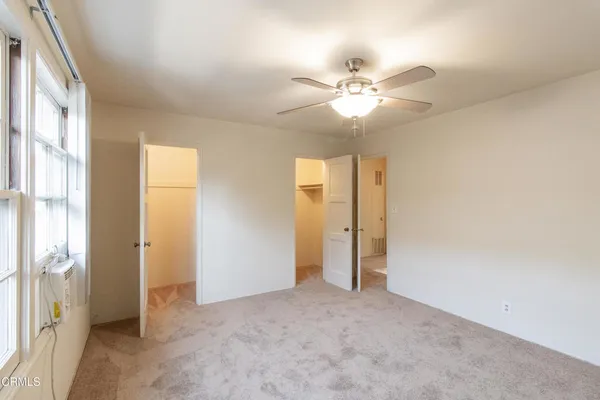 an empty room with closet and a chandelier fan