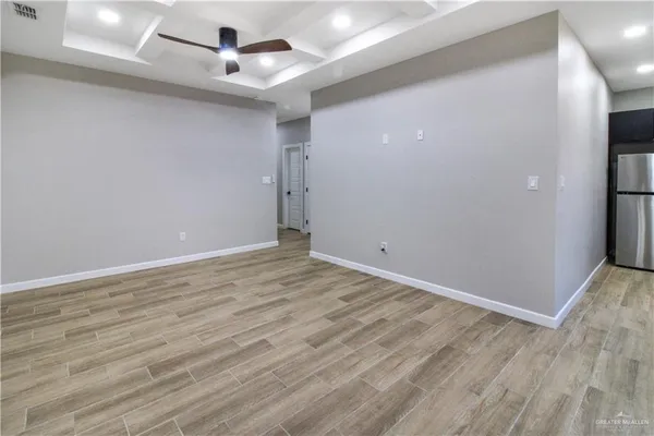 an empty room with wooden floor and ceiling fan
