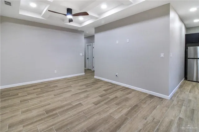 an empty room with wooden floor and ceiling fan