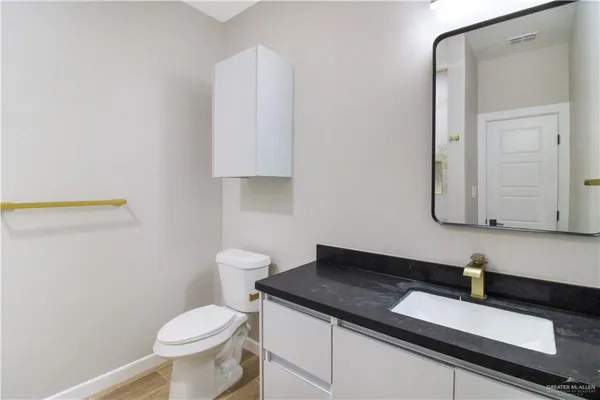 a bathroom with a granite countertop sink and a toilet