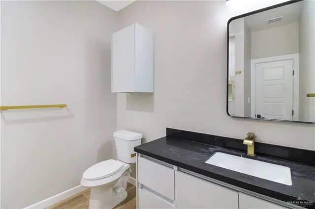 a bathroom with a granite countertop sink and a toilet