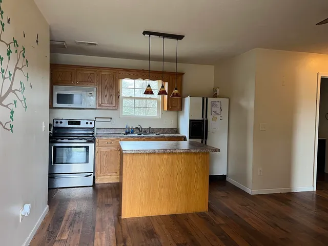 a kitchen with granite countertop a stove a sink and a refrigerator