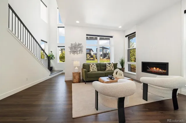 a living room with couches and a view of kitchen with wooden floor