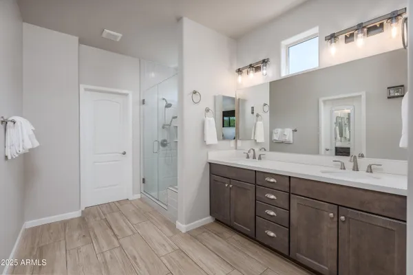 a spacious bathroom with a double vanity sink a mirror and a shower