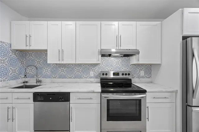 a kitchen with granite countertop white cabinets and black appliances