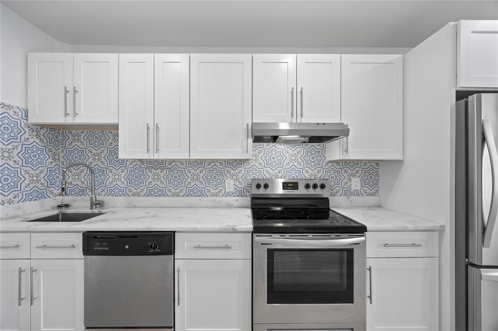 a kitchen with granite countertop white cabinets and black appliances