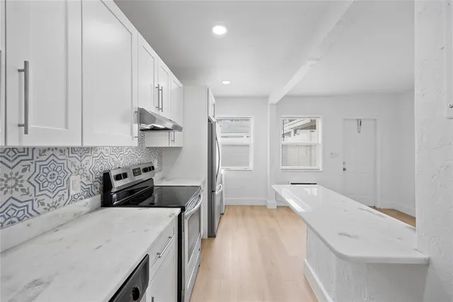 a kitchen with stainless steel appliances granite countertop a refrigerator a sink and white cabinets