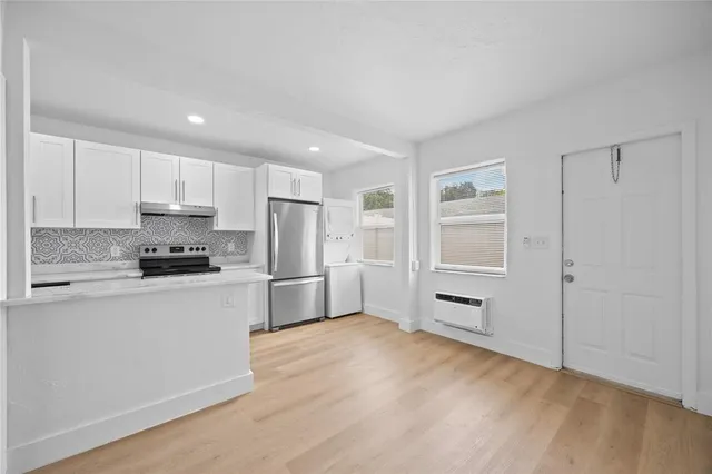 a kitchen with granite countertop a refrigerator and a stove top oven