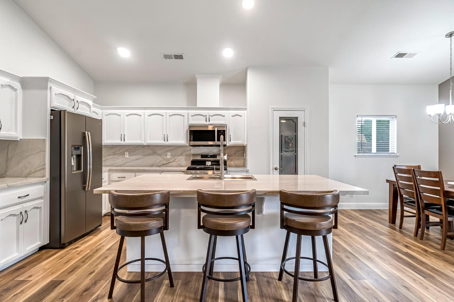 2634 Marie Drive Madera, CA 93637 - Photo 11 of 32 a kitchen with stainless steel appliances a dining table chairs stove refrigerator and cabinets