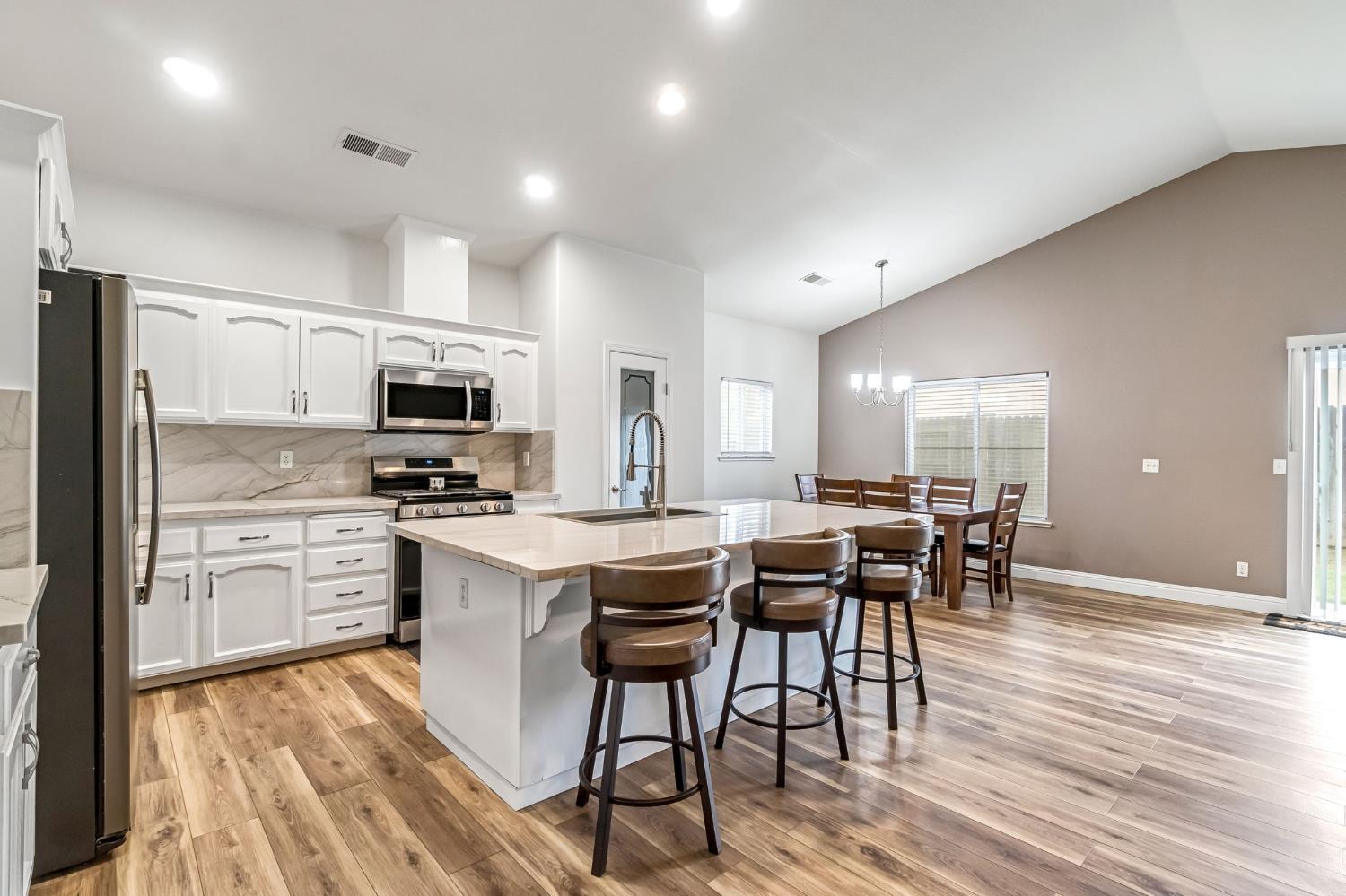 2634 Marie Drive Madera, CA 93637 - Photo 12 of 32 a kitchen with stainless steel appliances a dining table chairs stove refrigerator and cabinets