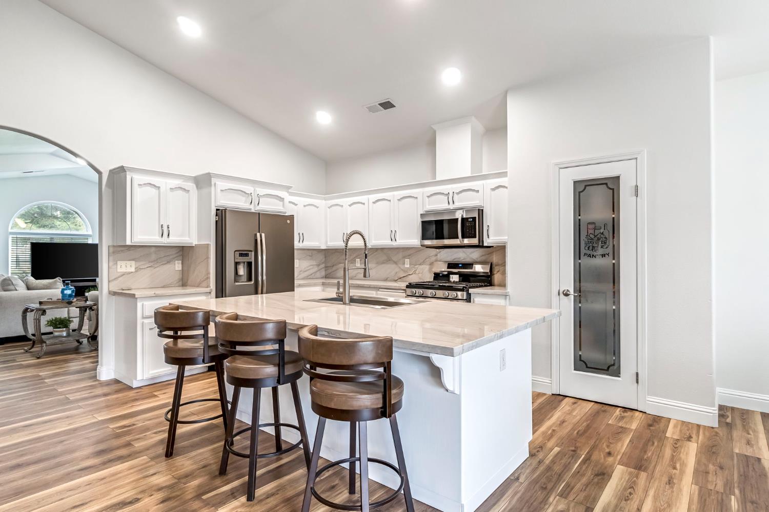 2634 Marie Drive Madera, CA 93637 - Photo 13 of 32 a kitchen with stainless steel appliances a stove top oven a refrigerator a sink and white cabinets with wooden floor