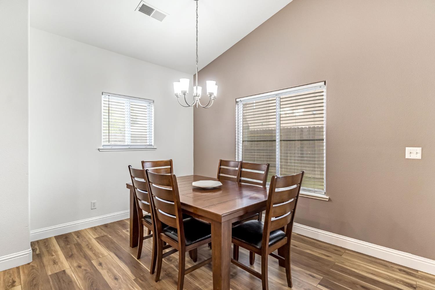 2634 Marie Drive Madera, CA 93637 - Photo 17 of 32 a dining room with wooden floor a chandelier a wooden table and chairs