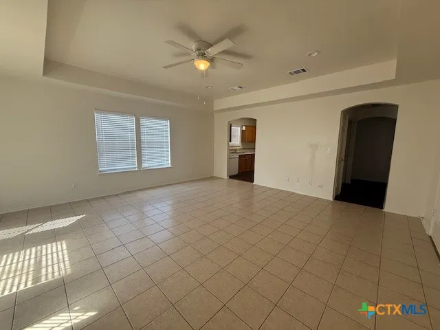 an empty room with windows and ceiling fan