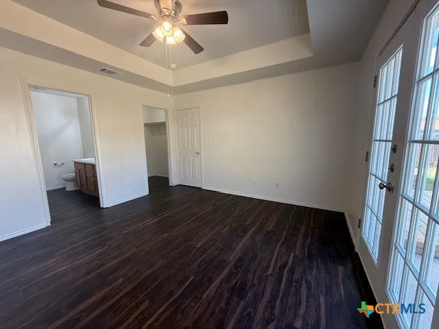 a view of an empty room with wooden floor and a ceiling fan