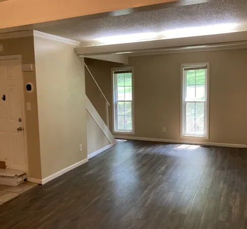 an empty room with wooden floor and windows