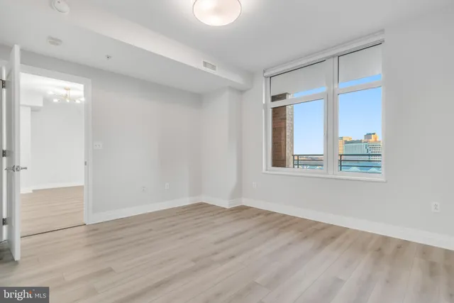 a view of an empty room with wooden floor and a window