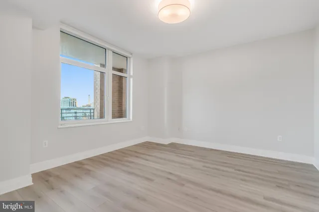 a view of an empty room with wooden floor and a window