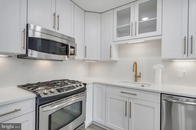 a kitchen with stainless steel appliances granite countertop white cabinets and a stove top oven