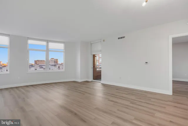 a view of an empty room with window and wooden floor