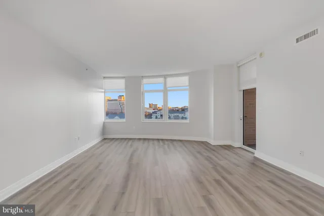 an empty room with wooden floor and windows