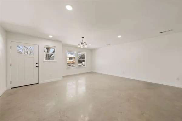 an empty room with kitchen view and windows