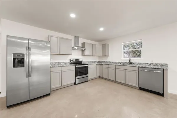 a large kitchen with a refrigerator and white cabinets