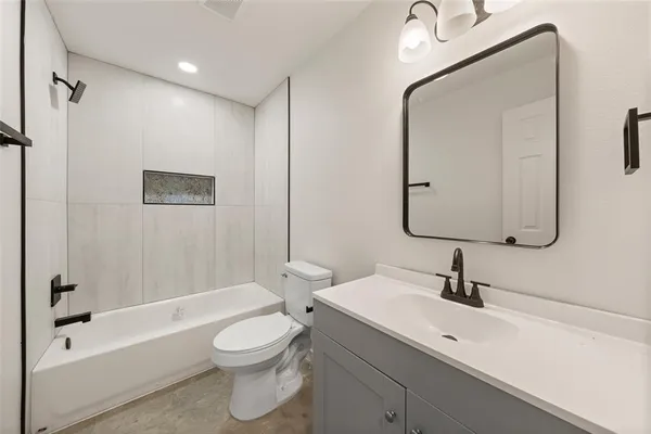 a bathroom with a toilet a sink a mirror and bathtub