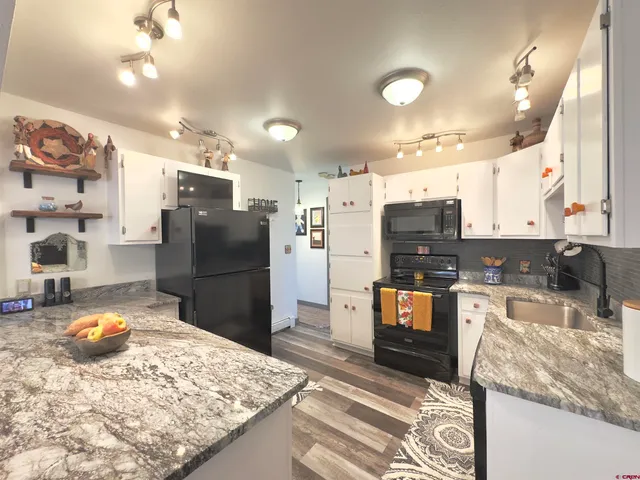 a kitchen with stainless steel appliances kitchen island granite countertop a refrigerator stove and sink