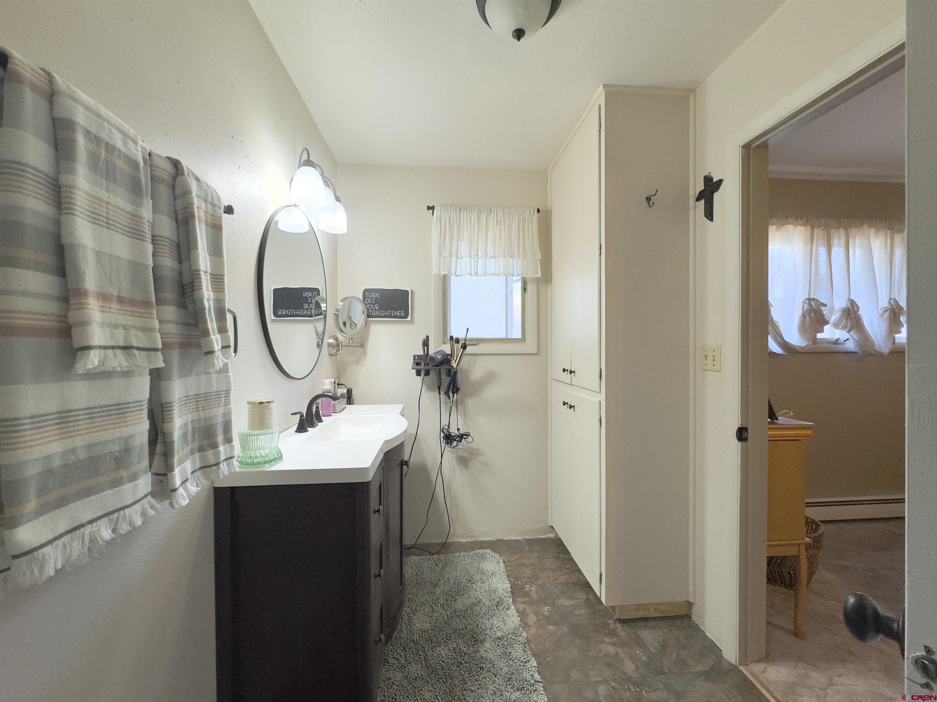 660 Columbia Avenue Del Norte, CO 81132 - Photo 21 of 31 a en suite bathroom with a sink a mirror and a shower