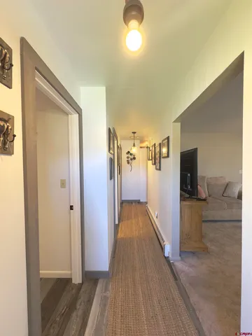 a view of a hallway with wooden floor and furniture